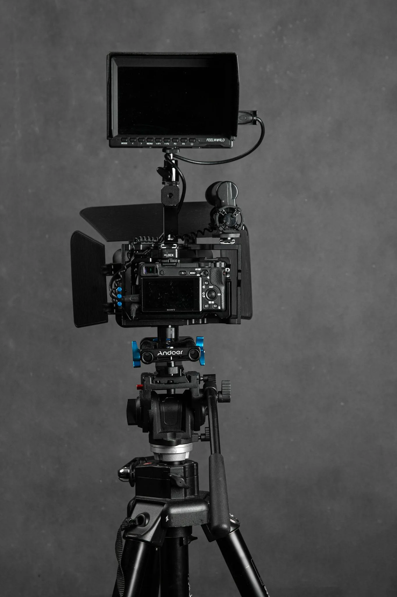 High-quality video camera on tripod with monitor in studio setting.